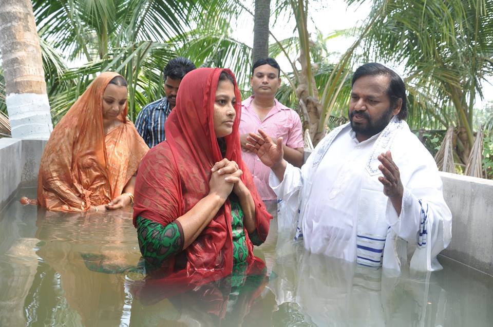 Brother Isaac performing baptism by immersion in a river